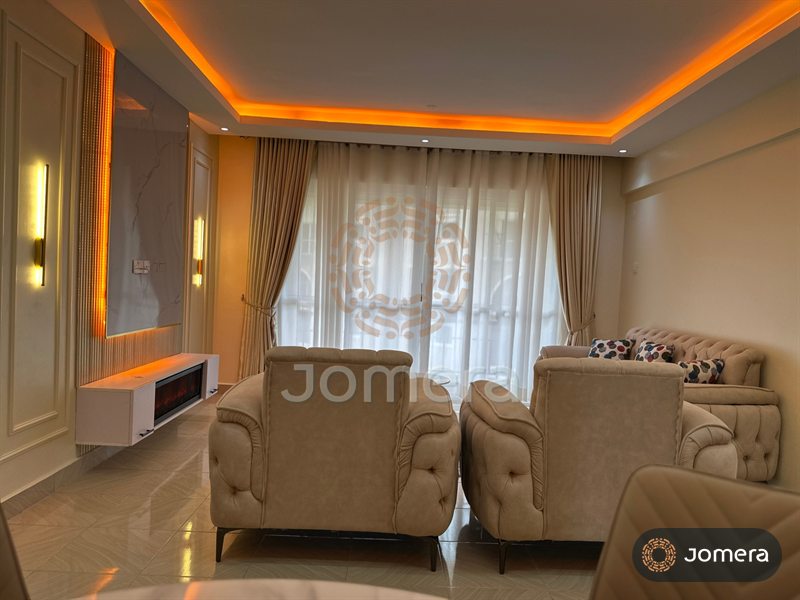Living room with tufted velvet armchairs and sofa, layered curtains, a warm-lit cove ceiling and a marble feature wall with fireplace