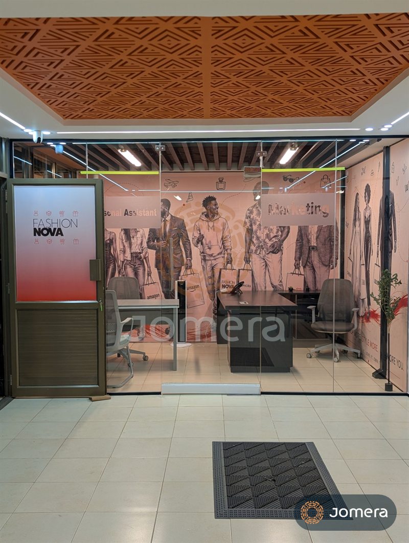 Glass-partitioned office under a CNC-cut terracotta ceiling panel, with timber slat ceiling and full-height wall graphics